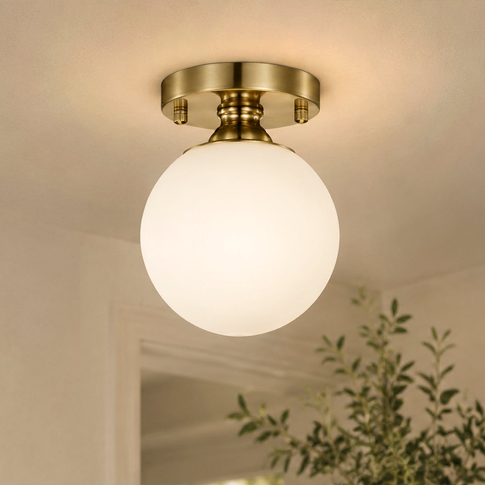 Brass glass globe flush mount ceiling light in a warm hallway